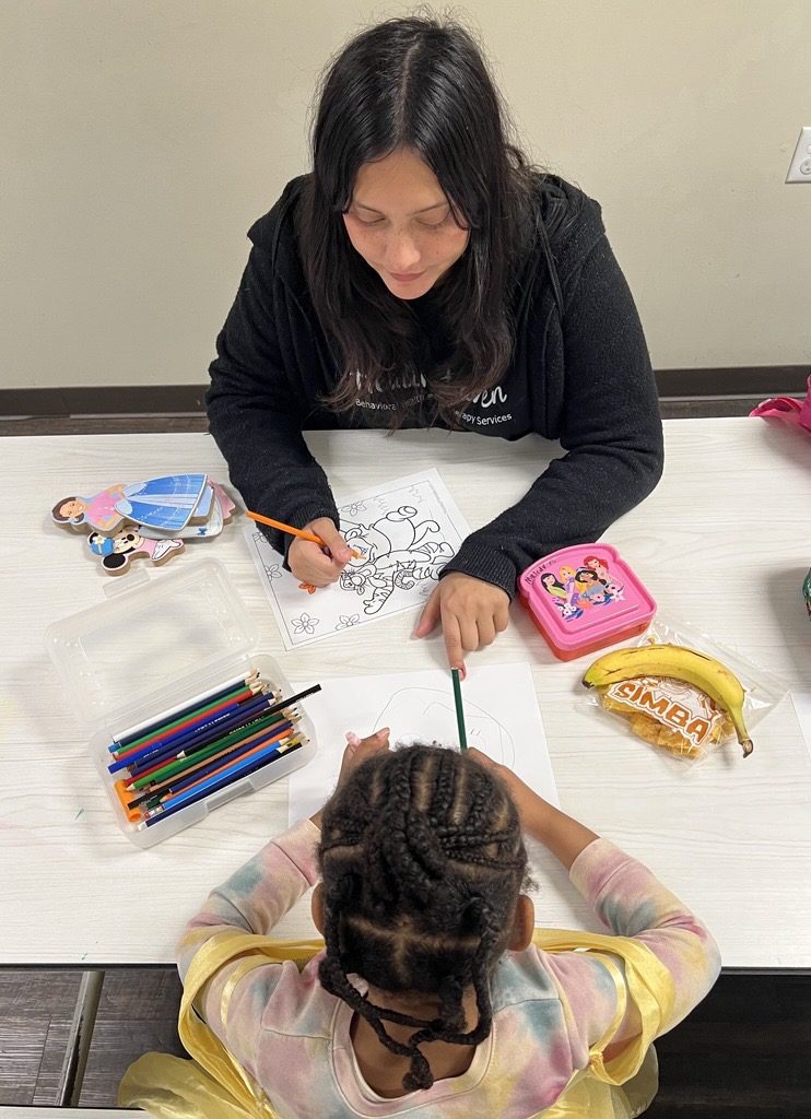 Registered Behavior Technician coloring with child/client.